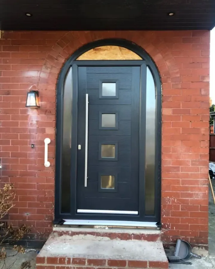 An anthracite composite front door in an arched brick porch
