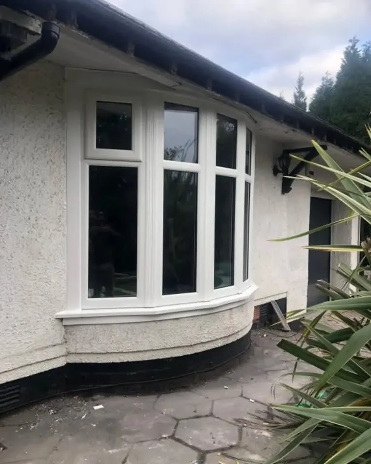 A white uPVC bay window on a rendered bungalow