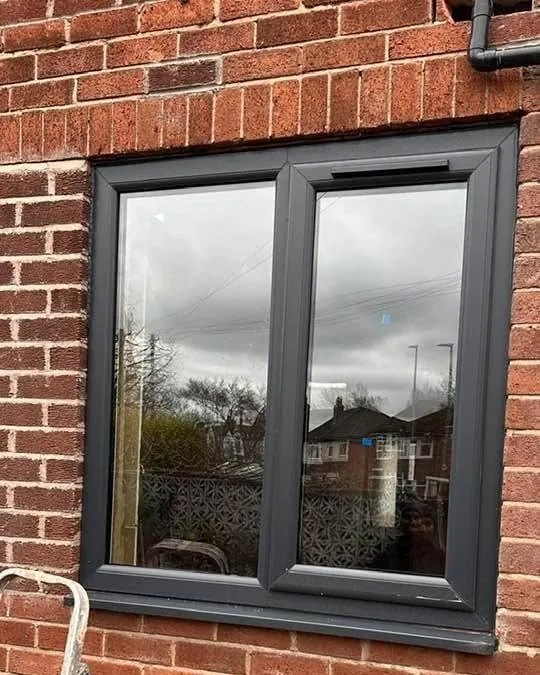 An anthracite grey uPVC window in brickwork