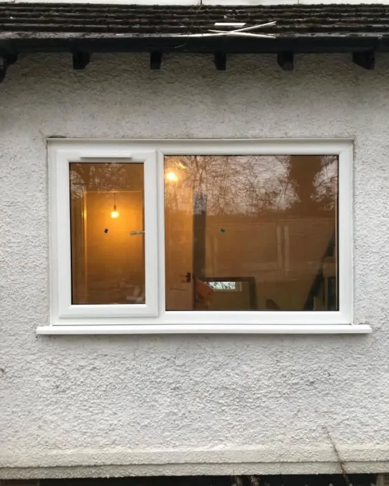 A double-glazed white window with a warmly lit room behind it